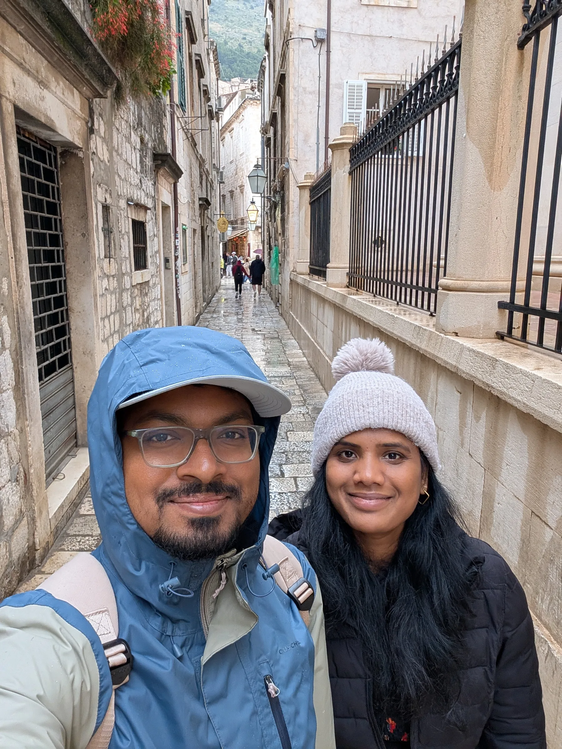 Selfie of two travellers in rain jackets on a narrow stone street in Dubrovnik’s old town