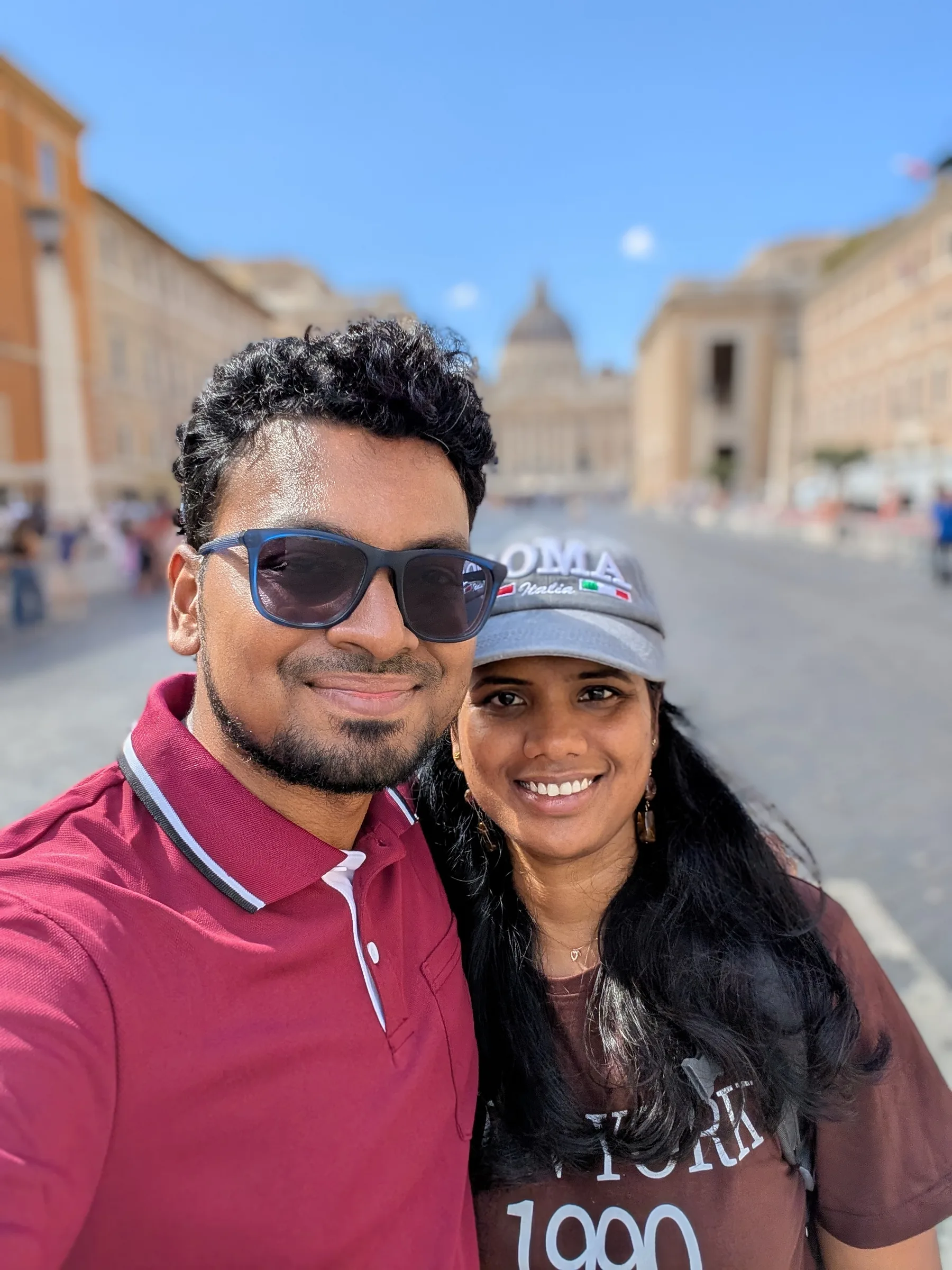 Selfie of two travellers on Via della Conciliazione with St. Peter’s Basilica behind them